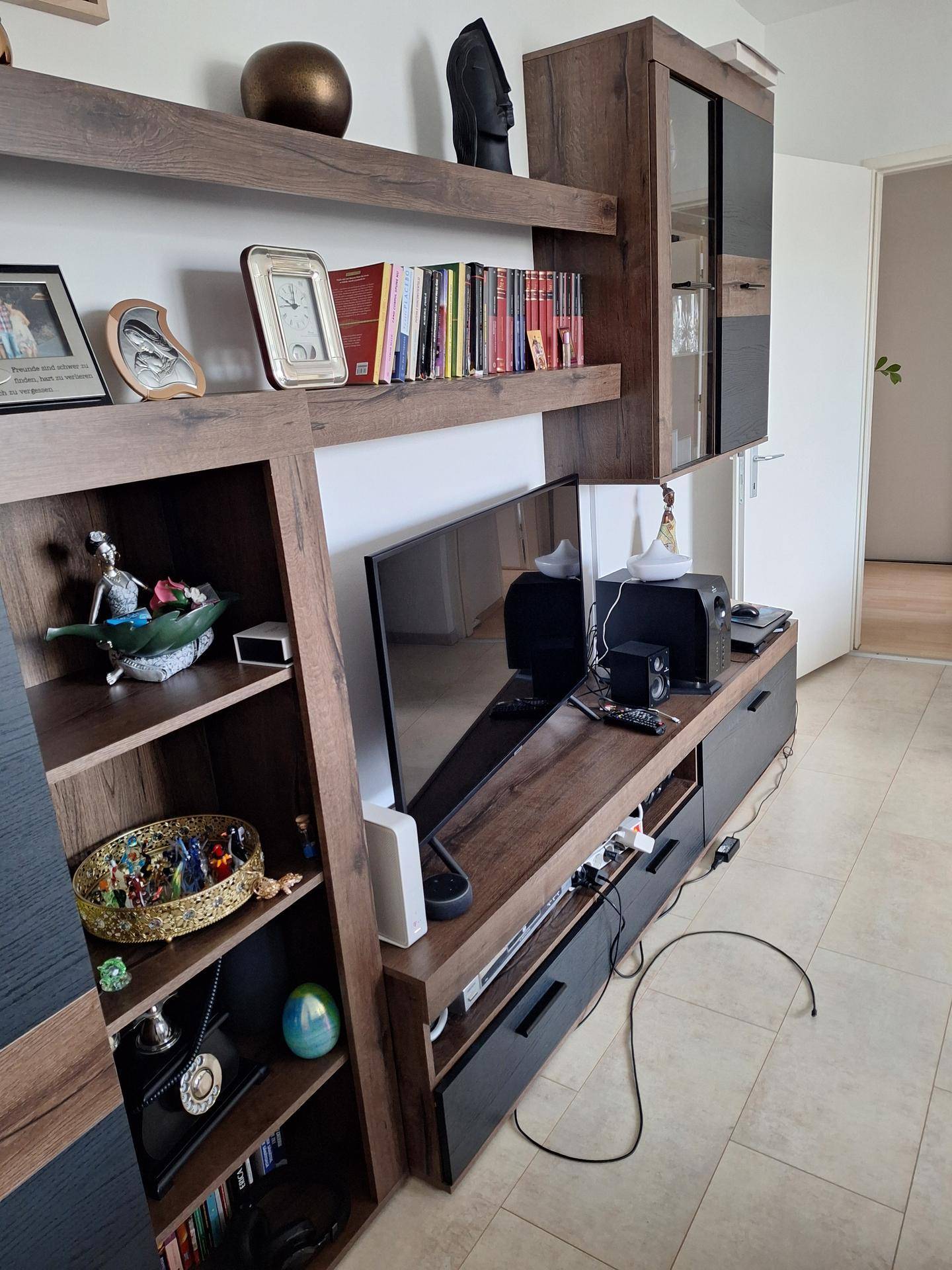 Wohnzimmerbereich mit modernem TV-Möbel, Regalen und dekorativen Elementen.
