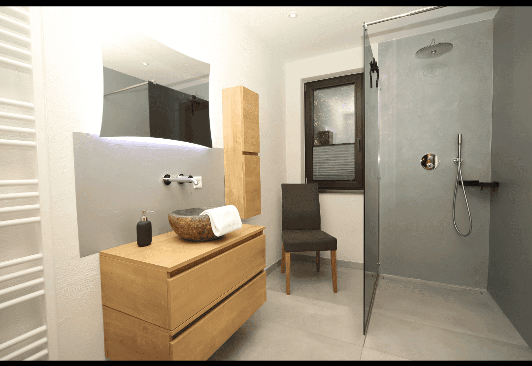 Modernes Badezimmer mit begehbarer Dusche, Holzwaschtisch und beleuchtetem Spiegel.