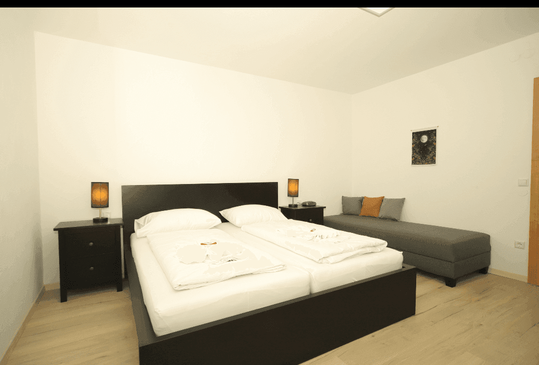 Helles Schlafzimmer mit Doppelbett, Nachttischen und Holzfußboden.
