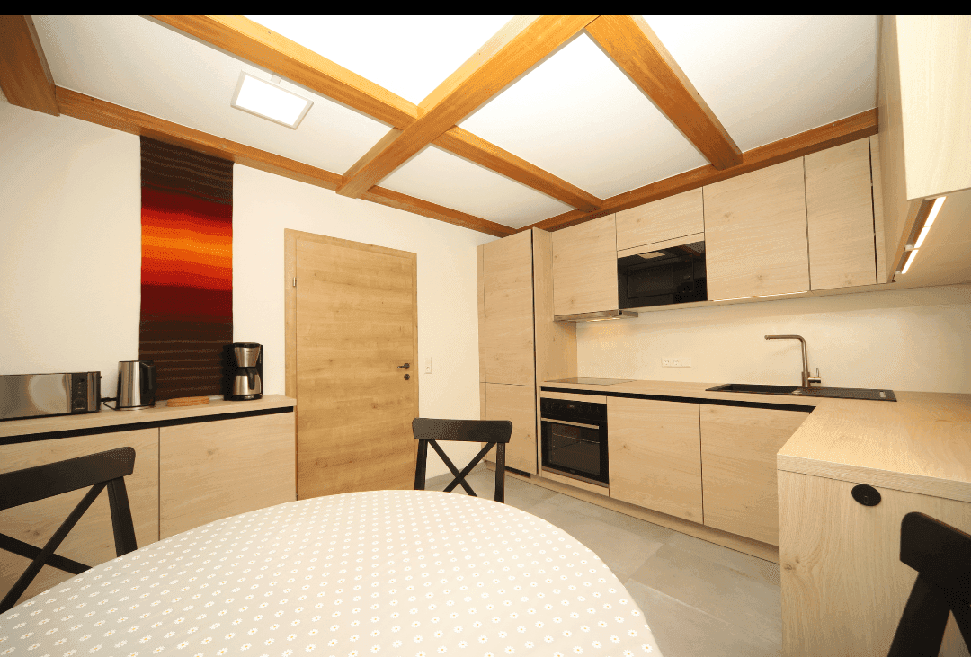 Moderne Wohnküche mit Holzbalkendecke, Essbereich und integrierten Geräten.