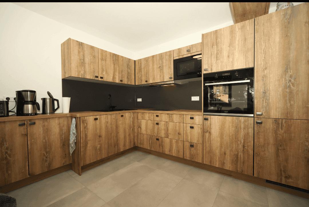 Geräumige Holzküche mit modernen Geräten, viel Stauraum und dunkler Arbeitsplatte.
