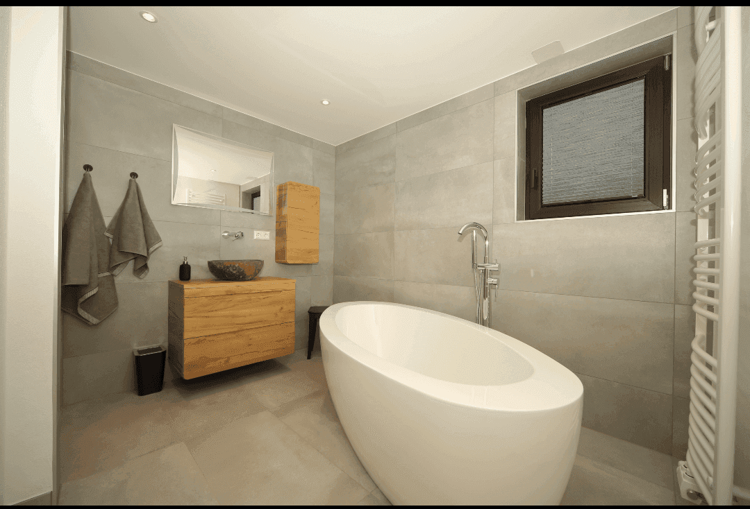Helles Badezimmer mit freistehender Badewanne, Holzwaschtisch und Fenster für Tageslicht.