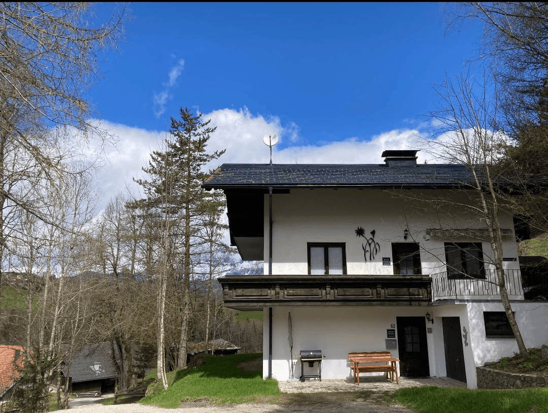 Traditionelles Haus im alpinen Stil mit Holzbalkonen unter blauem Himmel.