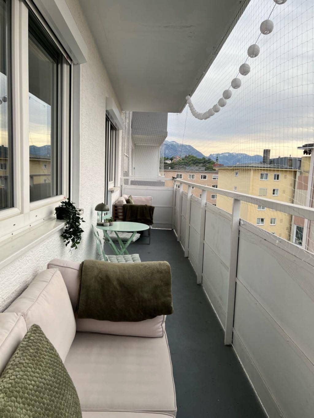 Langer Balkon mit Sitzgelegenheiten, Lichterkette und einem schönen Bergblick.