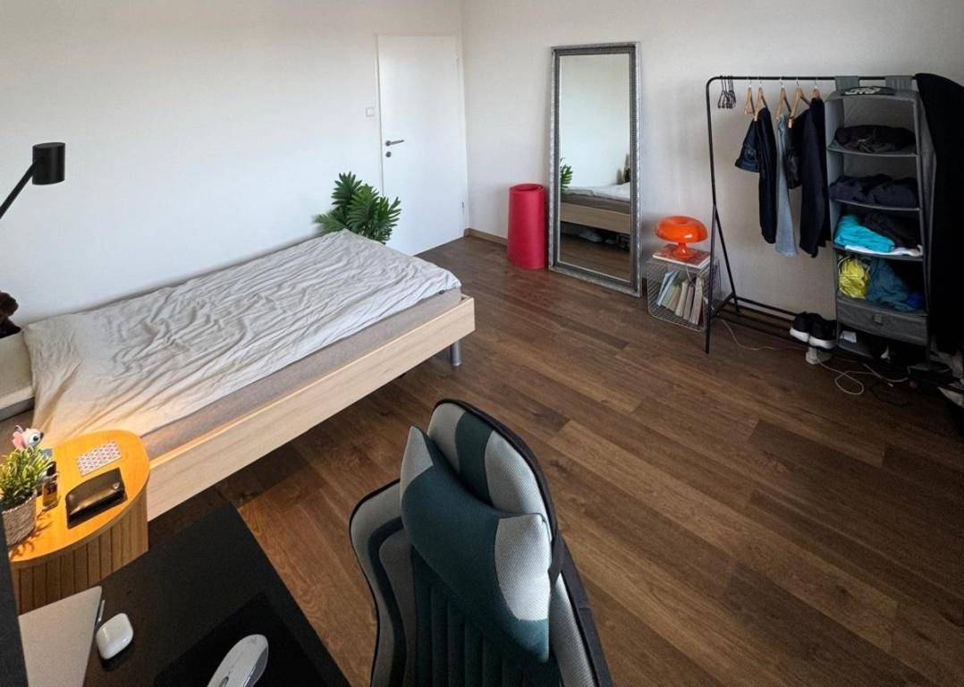 Schlafzimmer mit Einzelbett, großem Spiegel und praktischem Kleiderständer.