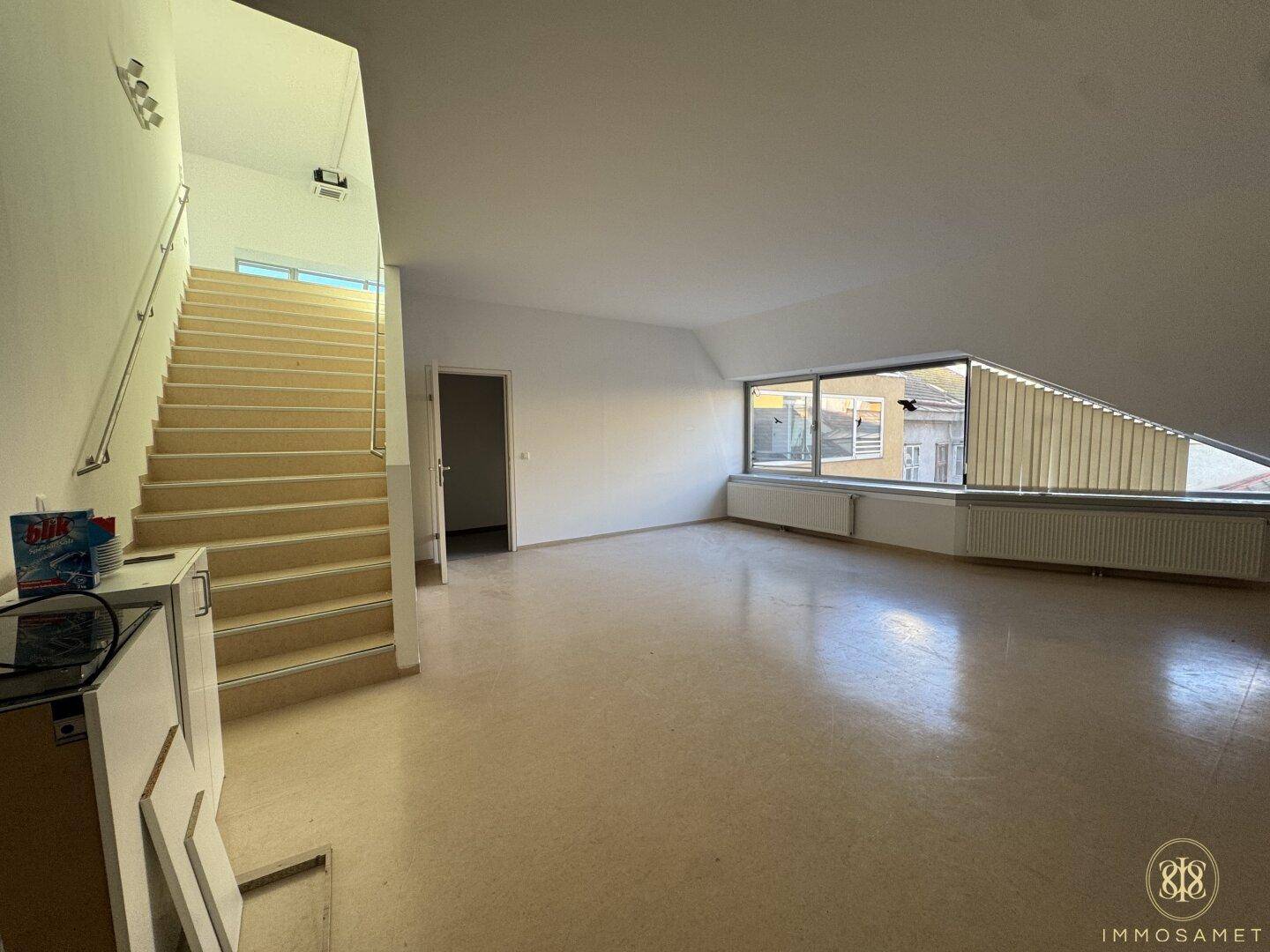 Geräumiger Eingangsbereich im Dachgeschoss mit Treppe und großen Fenstern, die eine helle Atmosphäre schaffen.