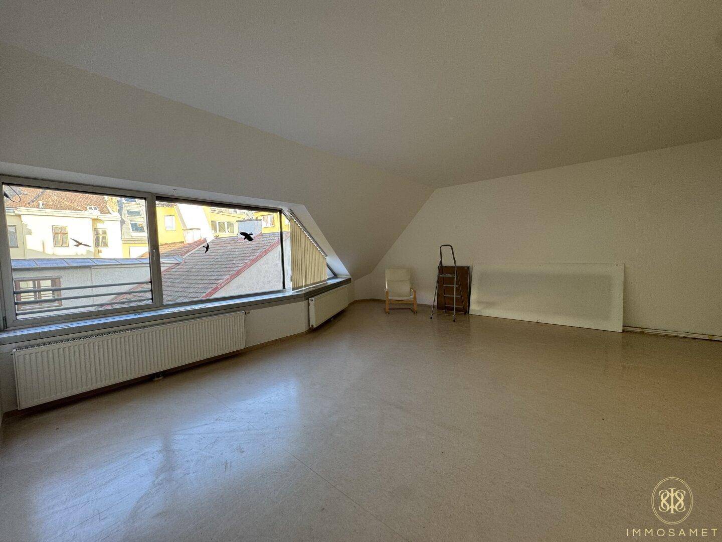 Großer, heller Raum im Dachgeschoss mit weitem Ausblick und schrägen Wänden, ideal für Büro oder Studio.