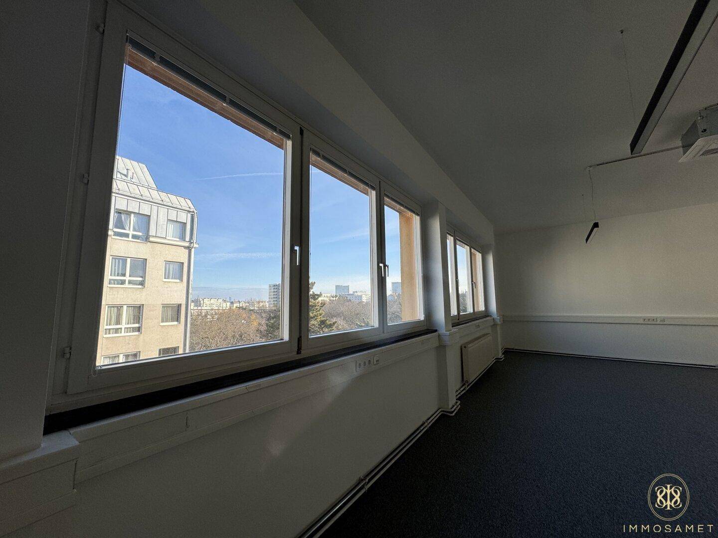 Heller Büroraum mit einer Reihe großer Fenster, die einen weiten Blick über die Stadt bieten.