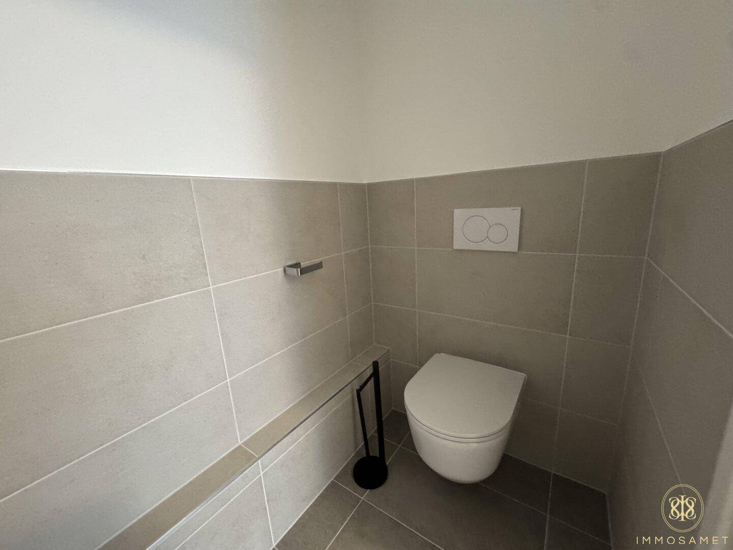 Modern geflieste Toilette mit wandhängendem WC und schlichtem Design in hellen Farbtönen.