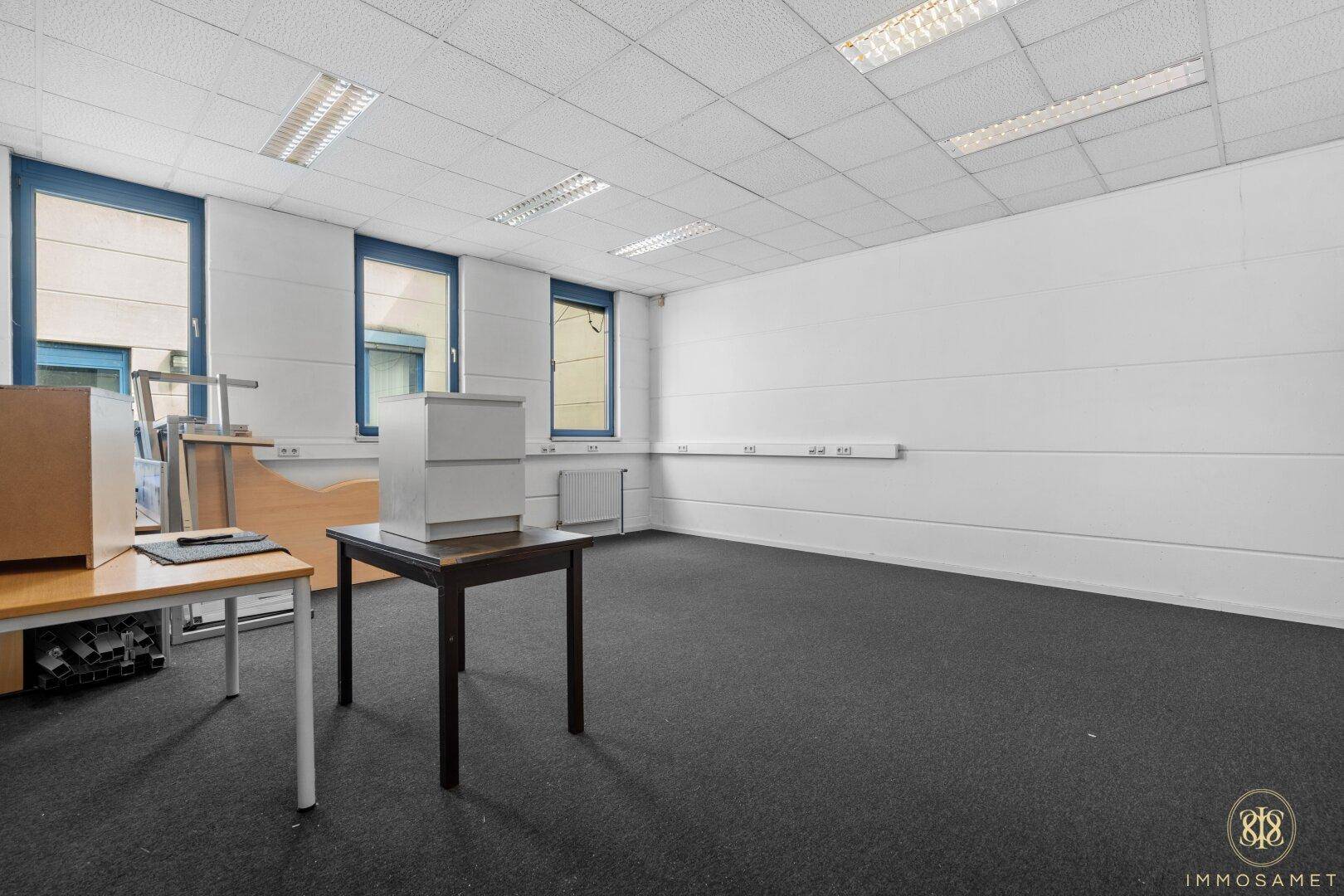 Unmöblierter Büroraum mit Teppichboden und Fenstern, bietet flexible Nutzungsmöglichkeiten für verschiedene Zwecke.