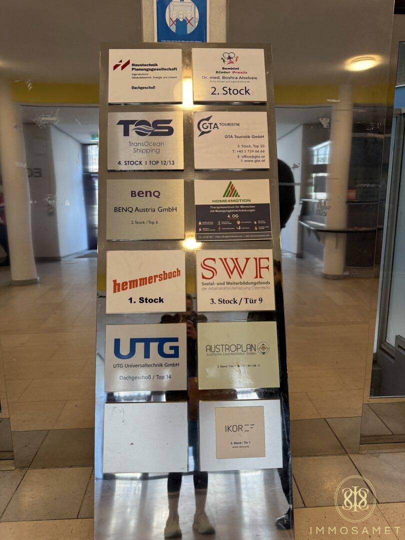 Detailansicht einer Spiegeltafel mit Firmenlogos und Stockwerksangaben im Eingangsbereich des Gebäudes.