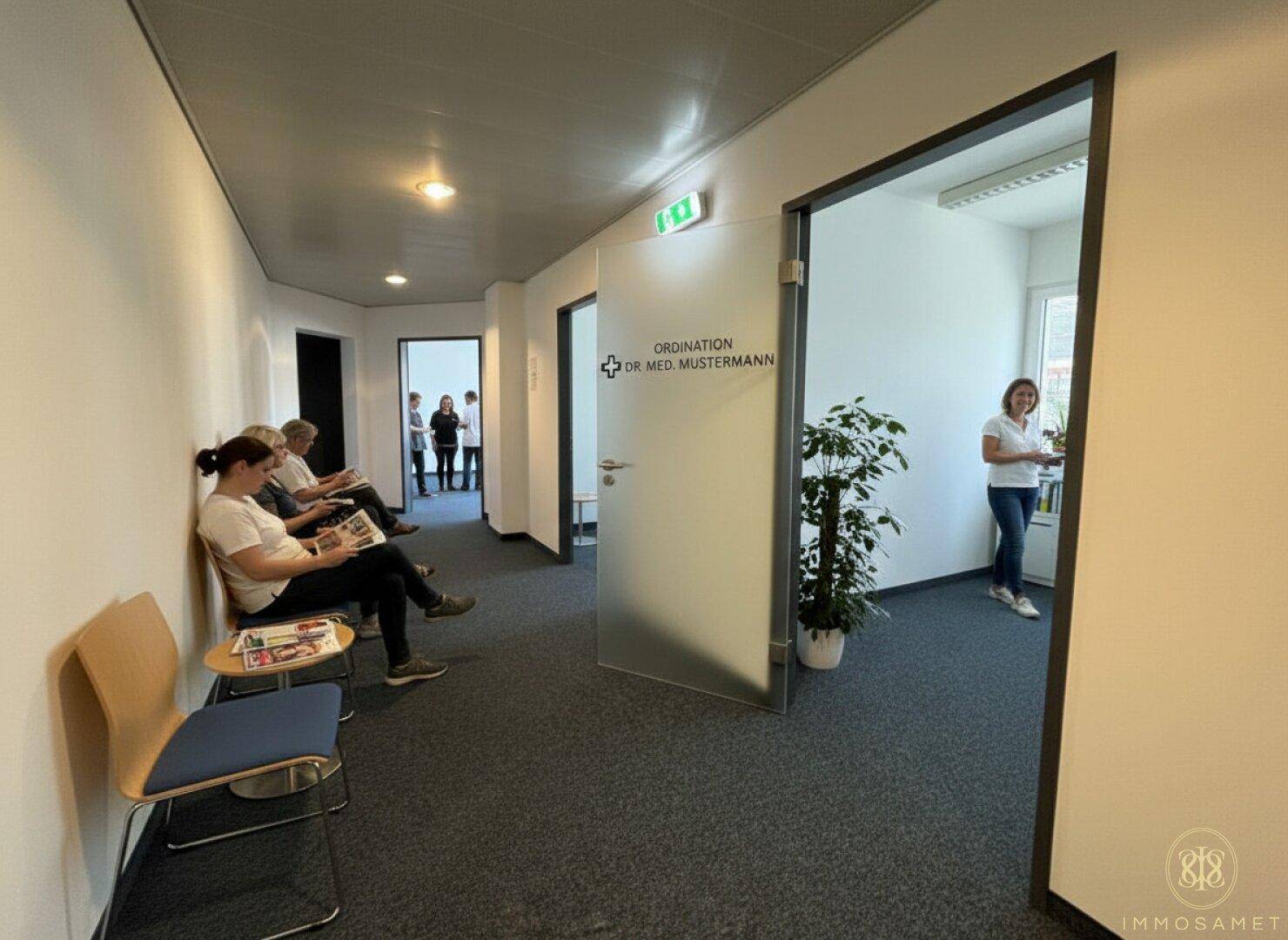 Wartebereich in einem Flur mit Sitzgelegenheiten und einer Tür zu einer Arztpraxis.