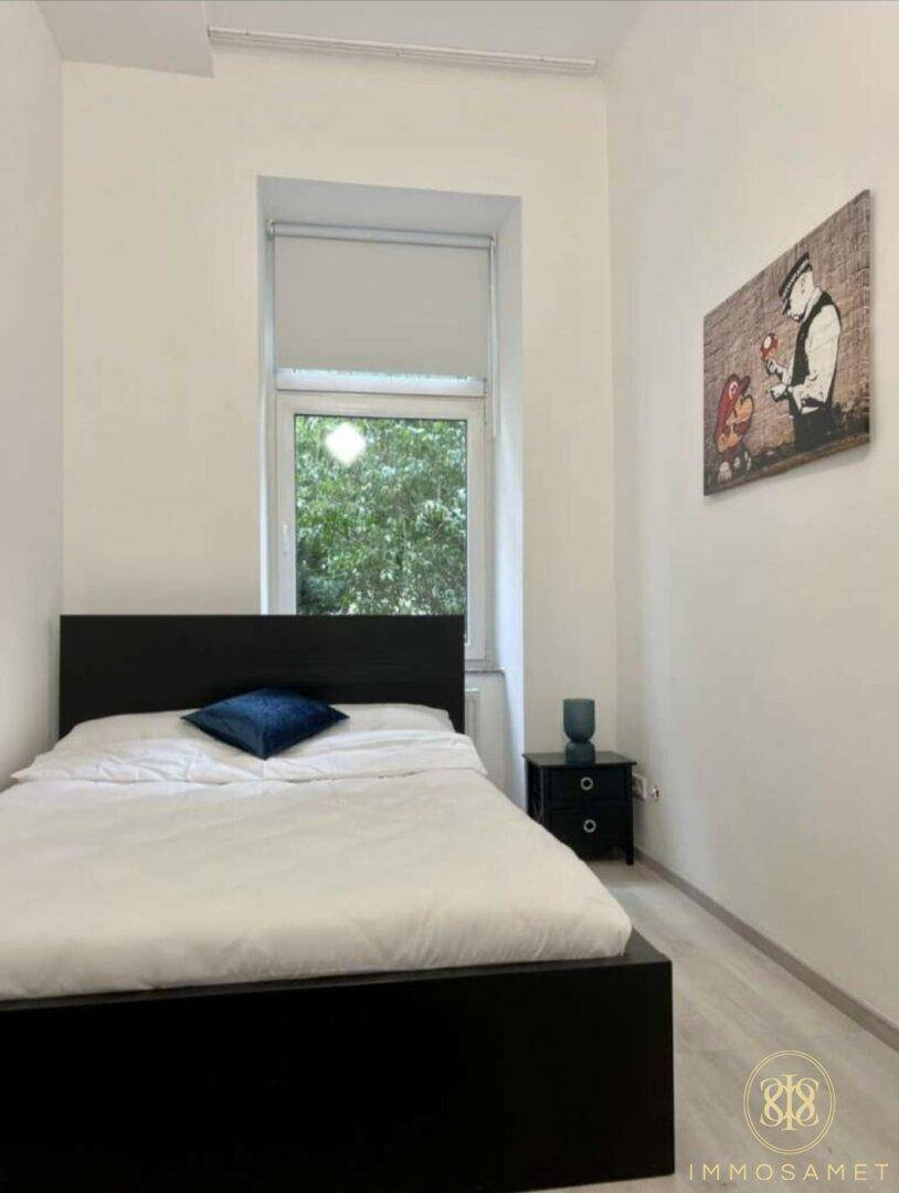 Helles Schlafzimmer mit Einzelbett, Fenster und moderner Wanddekoration.