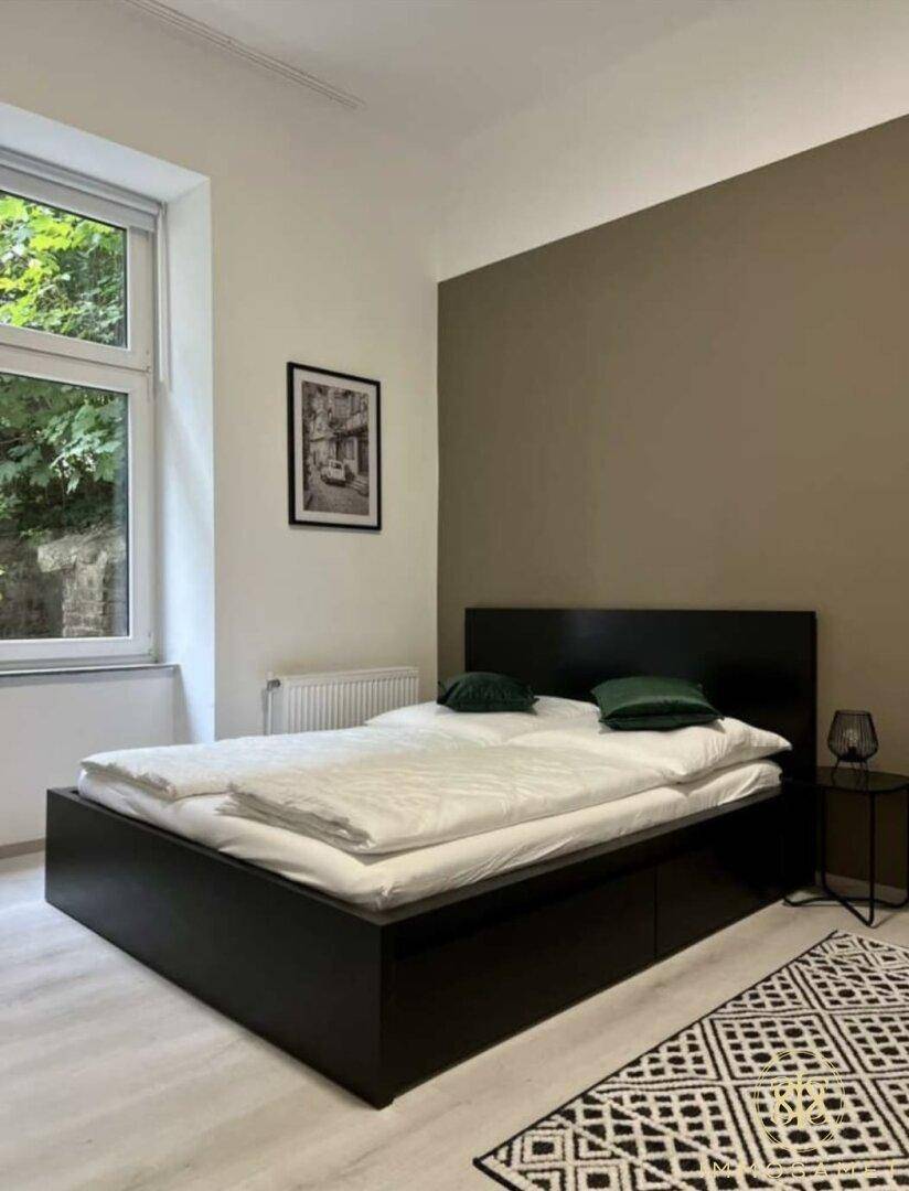 Gemütliches Schlafzimmer mit Doppelbett, Fenster und einer Akzentwand in warmem Farbton.