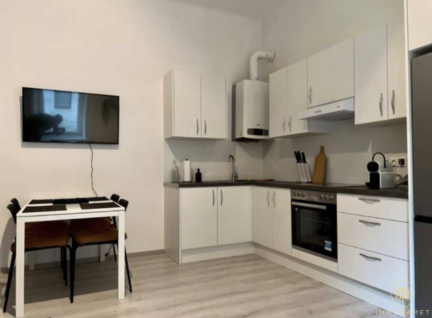 Gut ausgestattete Küche mit weißen Schränken, Kühlschrank und Essbereich für den täglichen Gebrauch.