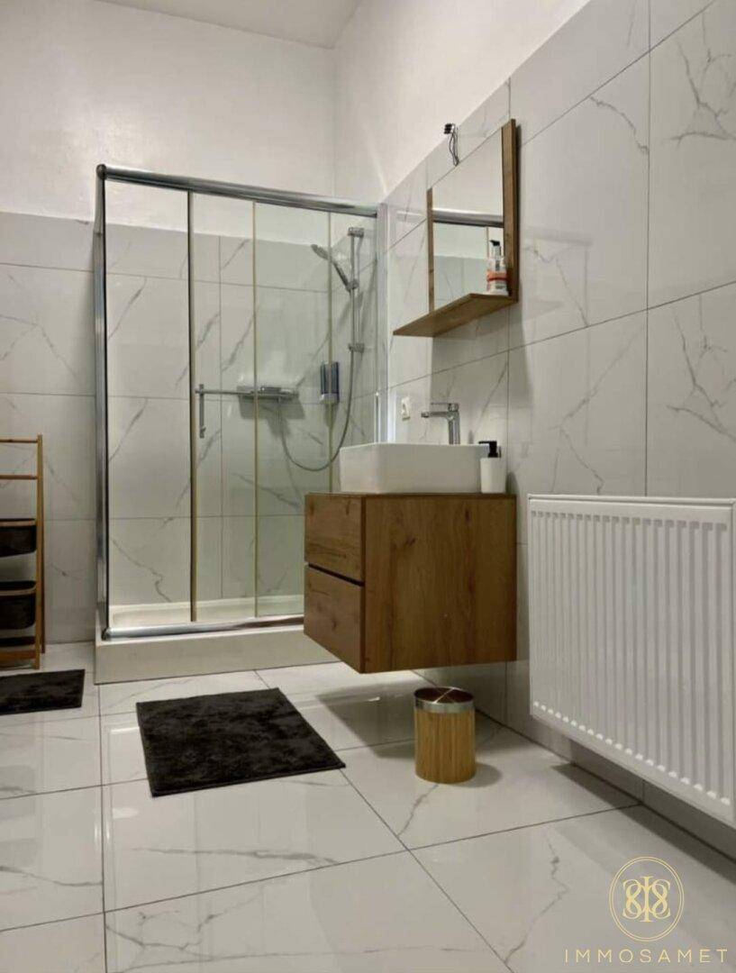 Modernes Badezimmer mit großer Duschkabine, schwebendem Waschtisch und eleganten Fliesen.