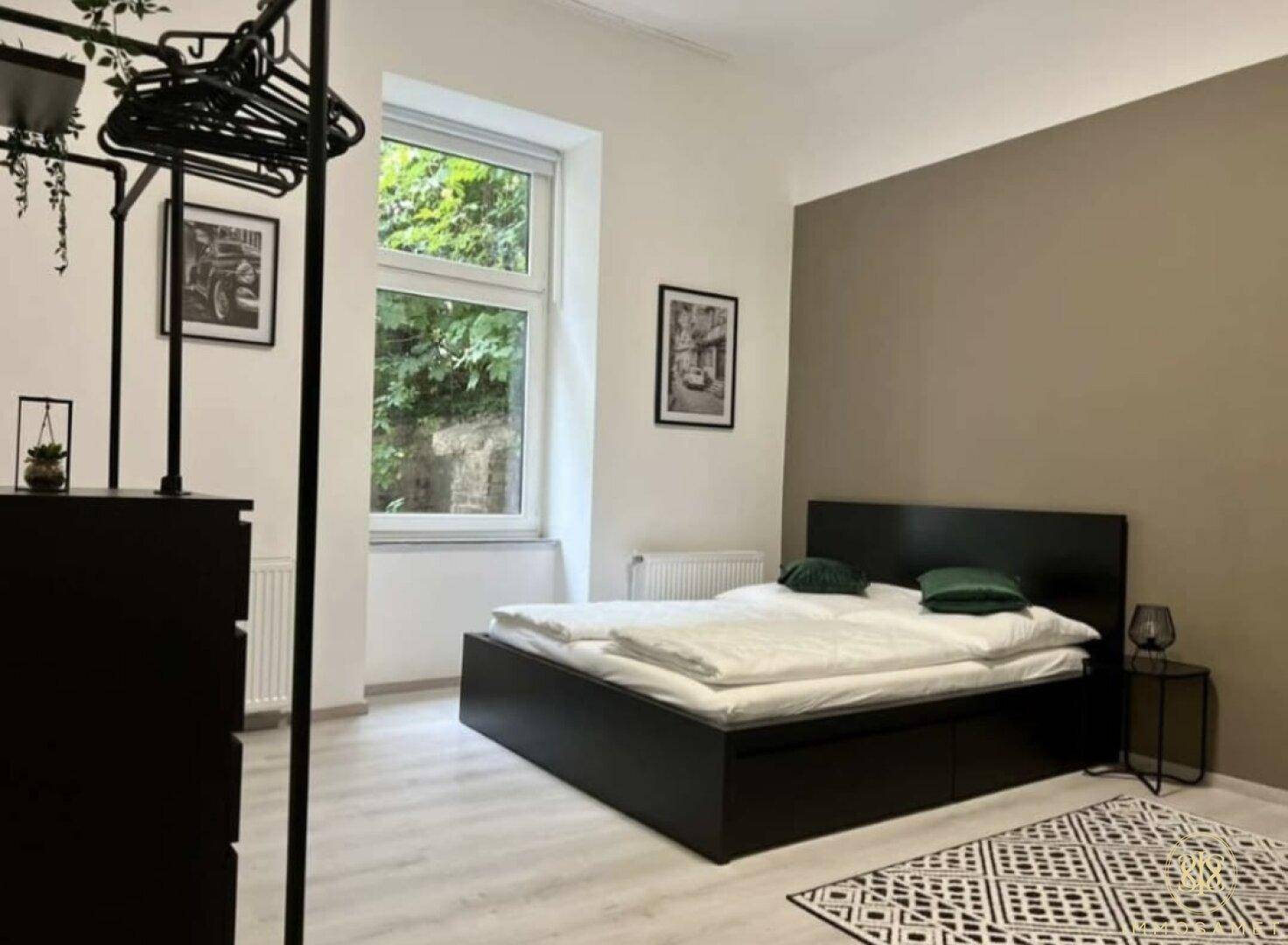 Schlafzimmer mit Doppelbett und offenem Kleiderschrank, das viel Tageslicht durch das Fenster erhält.