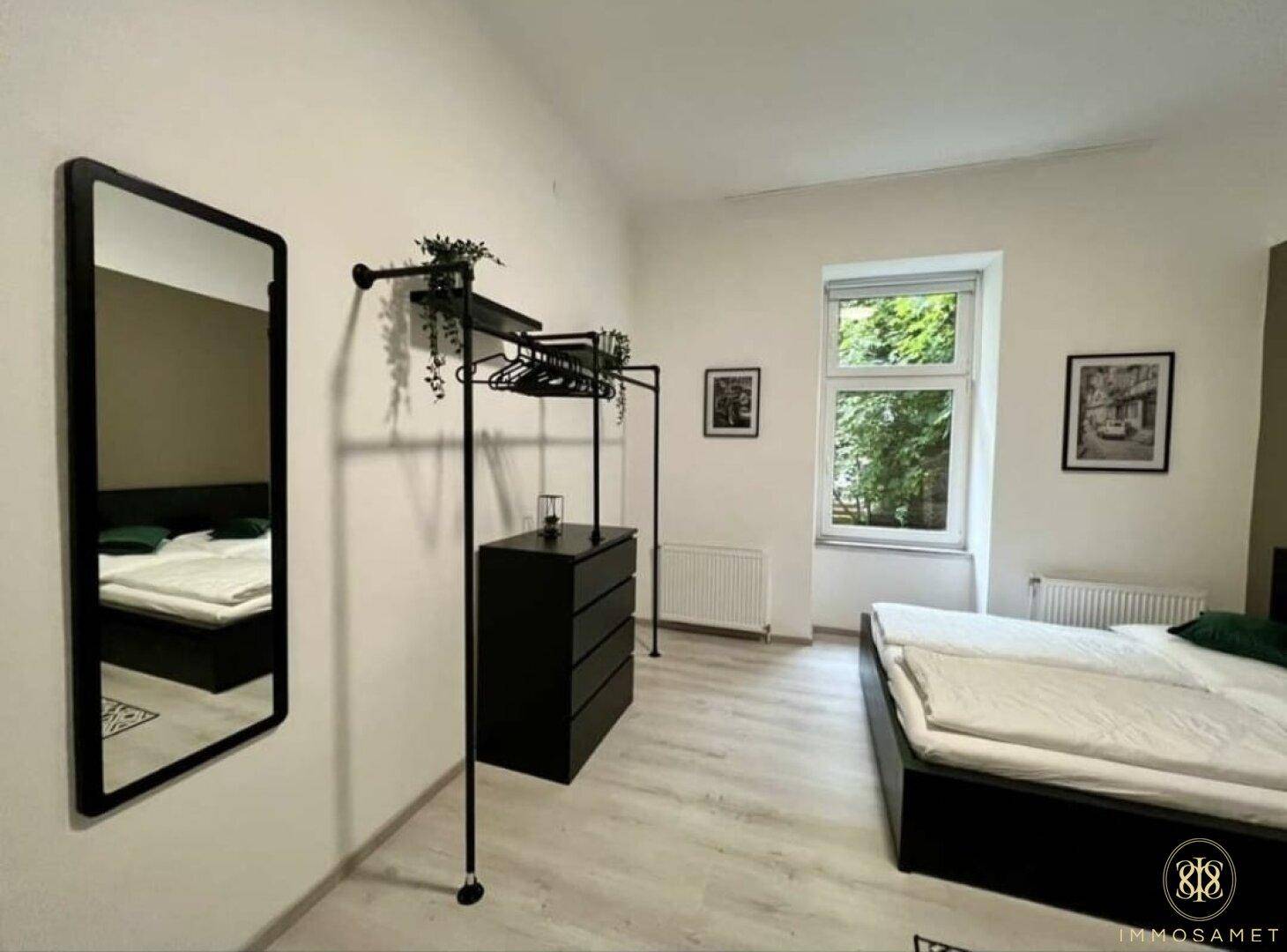 Schlafzimmer mit Doppelbett, großem Spiegel und praktischem offenem Kleiderschrank-System.