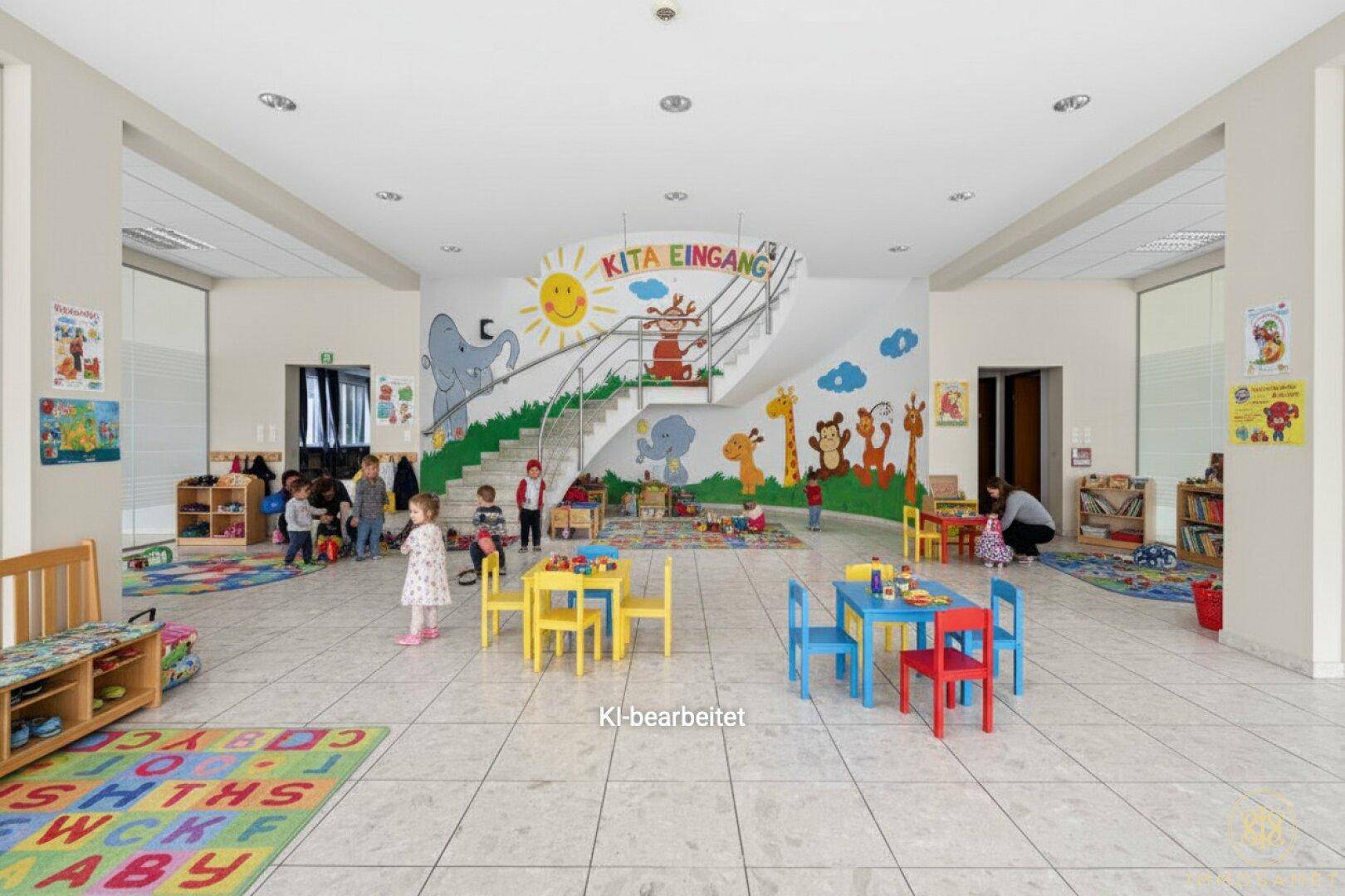 Heller Eingangsbereich eines Kindergartens mit bunter Wandmalerei, Treppe und Kindermöbeln.