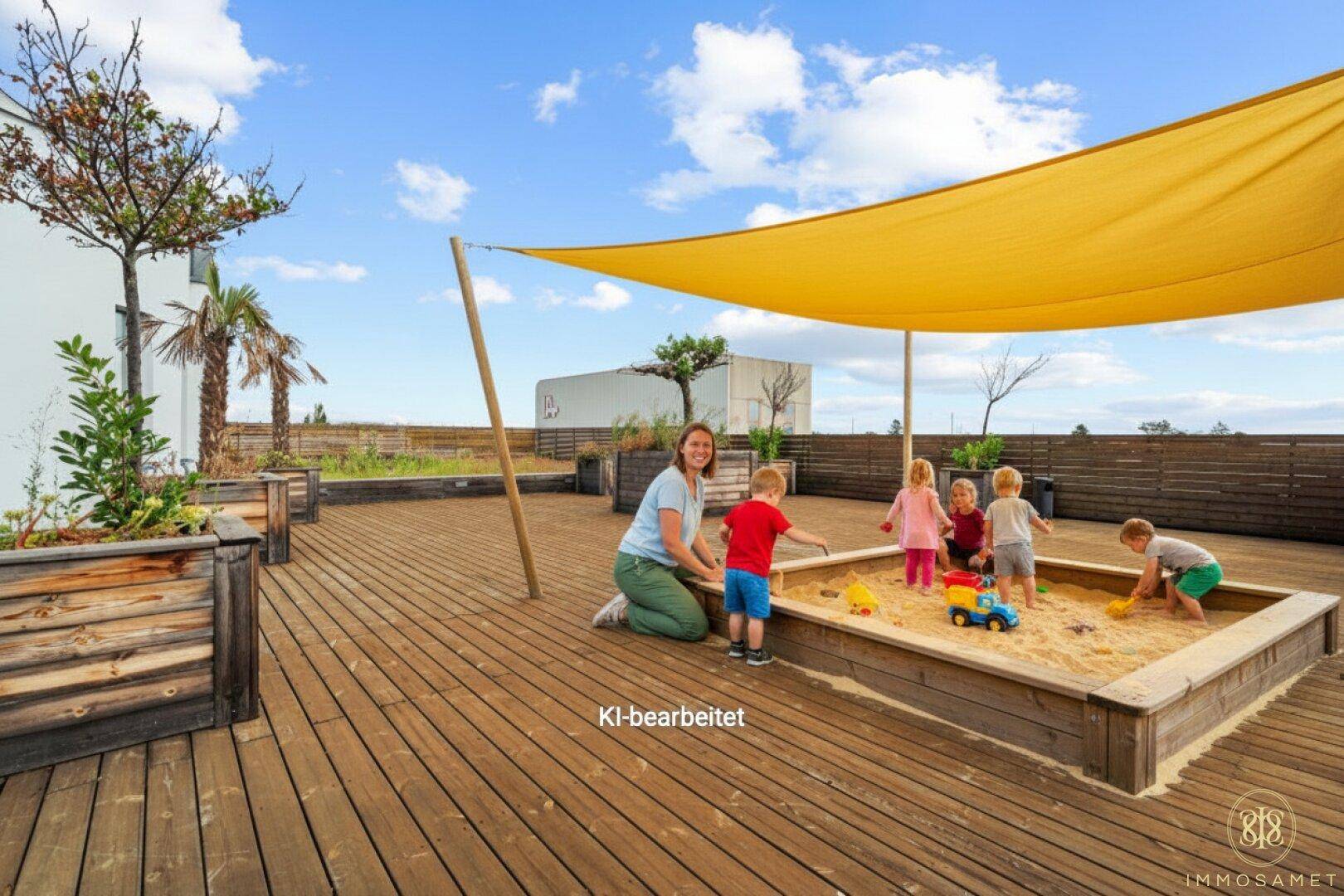 Außenbereich mit großem Sandkasten, Holzterrasse und Sonnensegel, ideal für Kinder zum Spielen.