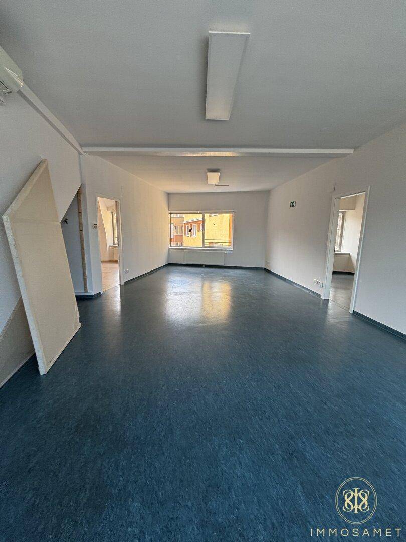 Großer, offener Raum mit dunklem Bodenbelag und mehreren Türen, ideal für flexible Nutzung.