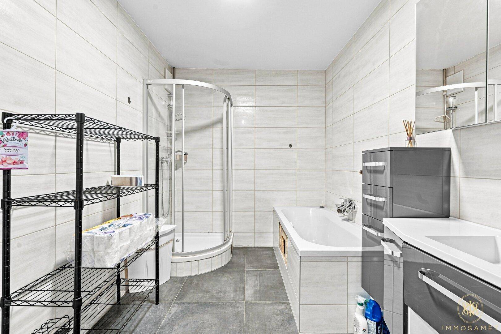 Helles Badezimmer mit Badewanne, Dusche und modernen Fliesen, die eine saubere Atmosphäre schaffen.