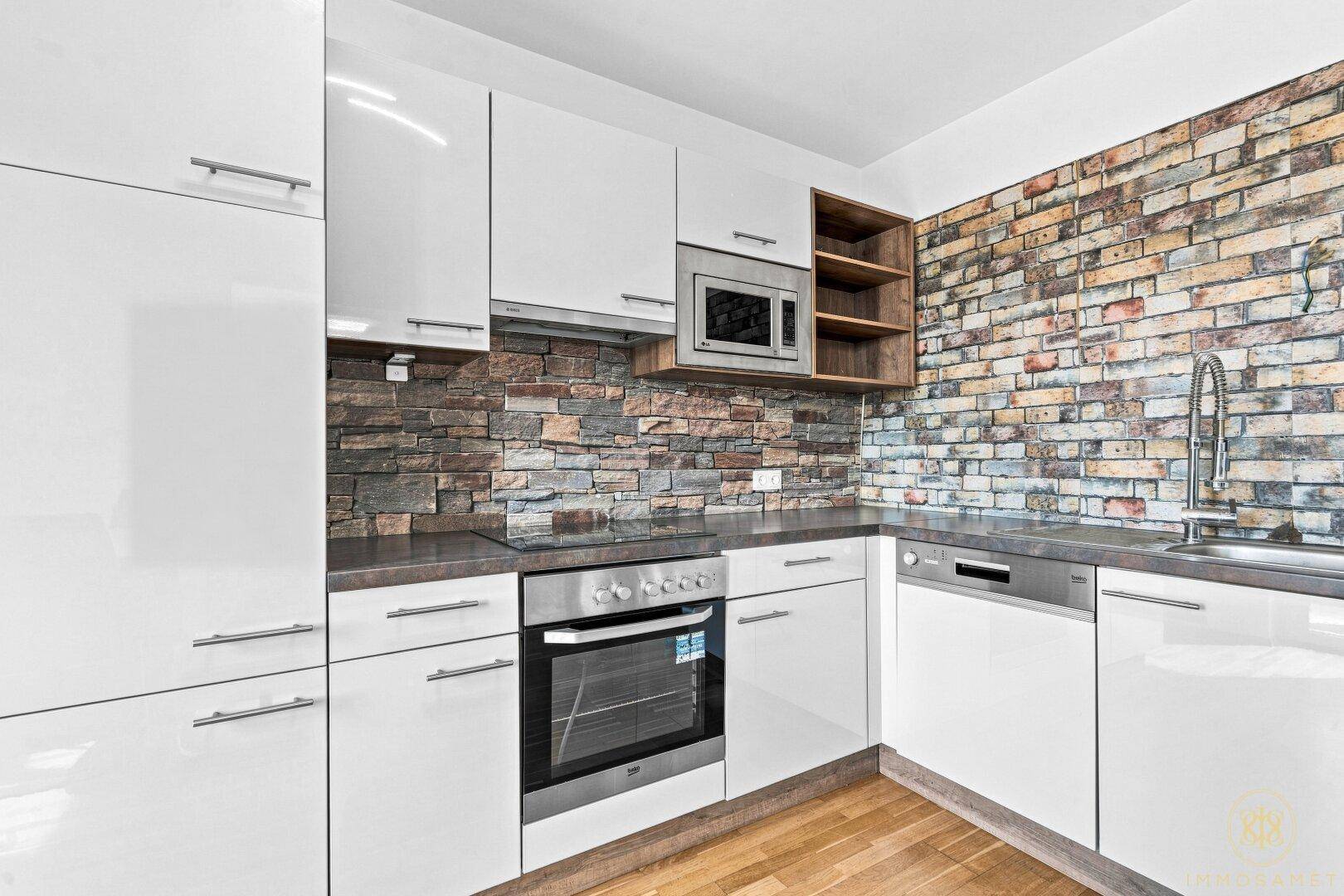 Moderne Einbauküche mit weißen Hochglanzfronten, Backofen, Geschirrspüler und Mikrowelle.