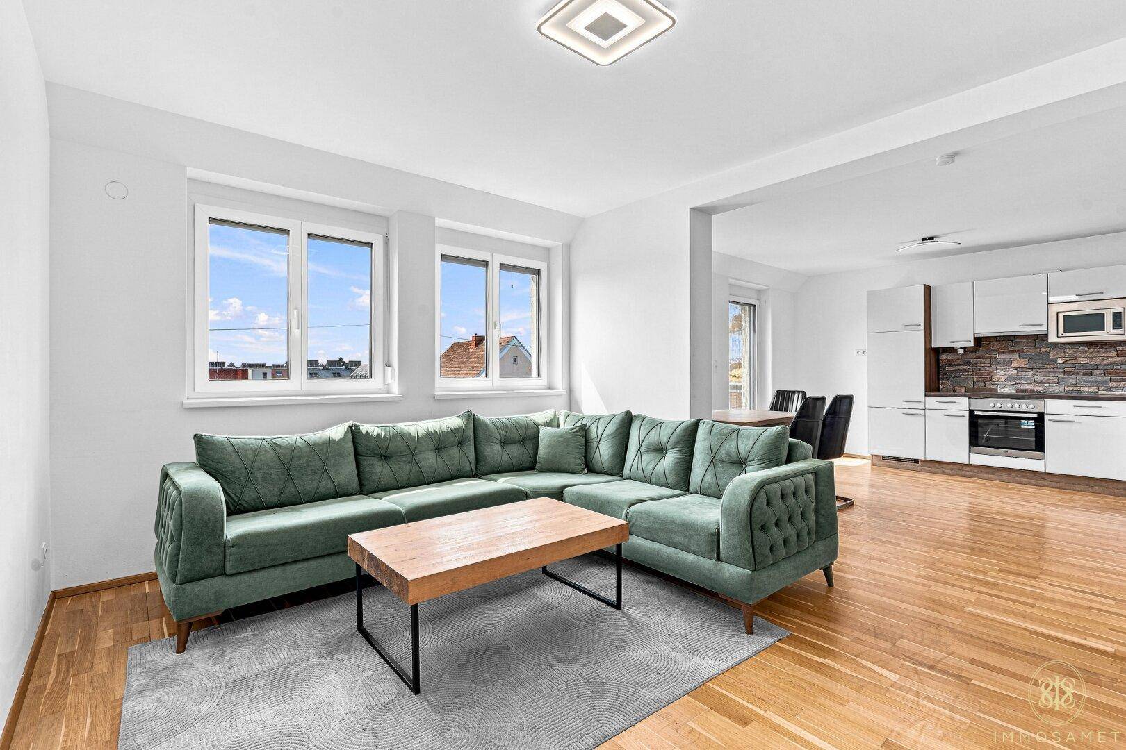 Heller Wohnbereich mit großem Sofa, Couchtisch und offener Verbindung zur Küche.