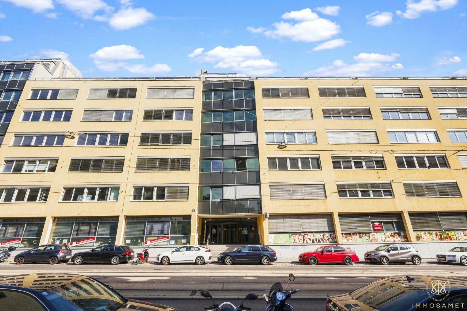 Fassade eines großen Geschäftsgebäudes mit vielen Fenstern und gelber Außenverkleidung.
