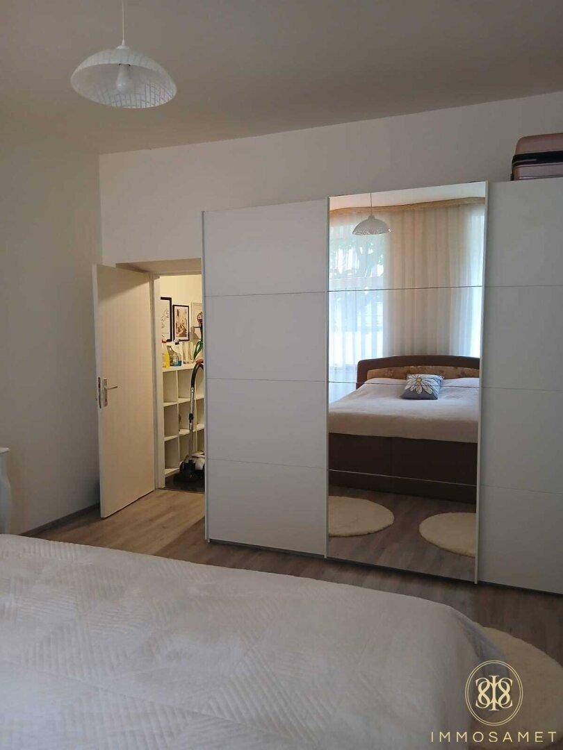 Schlafzimmer mit einem großen, modernen Spiegelschrank, der den Raum optisch vergrößert und viel Stauraum bietet.