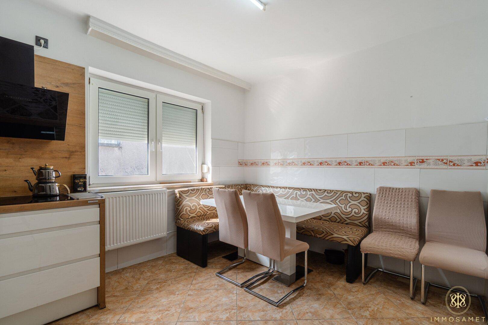 Gemütlicher Essbereich in der Küche mit Eckbank, Esstisch und zusätzlichen Stühlen am Fenster.