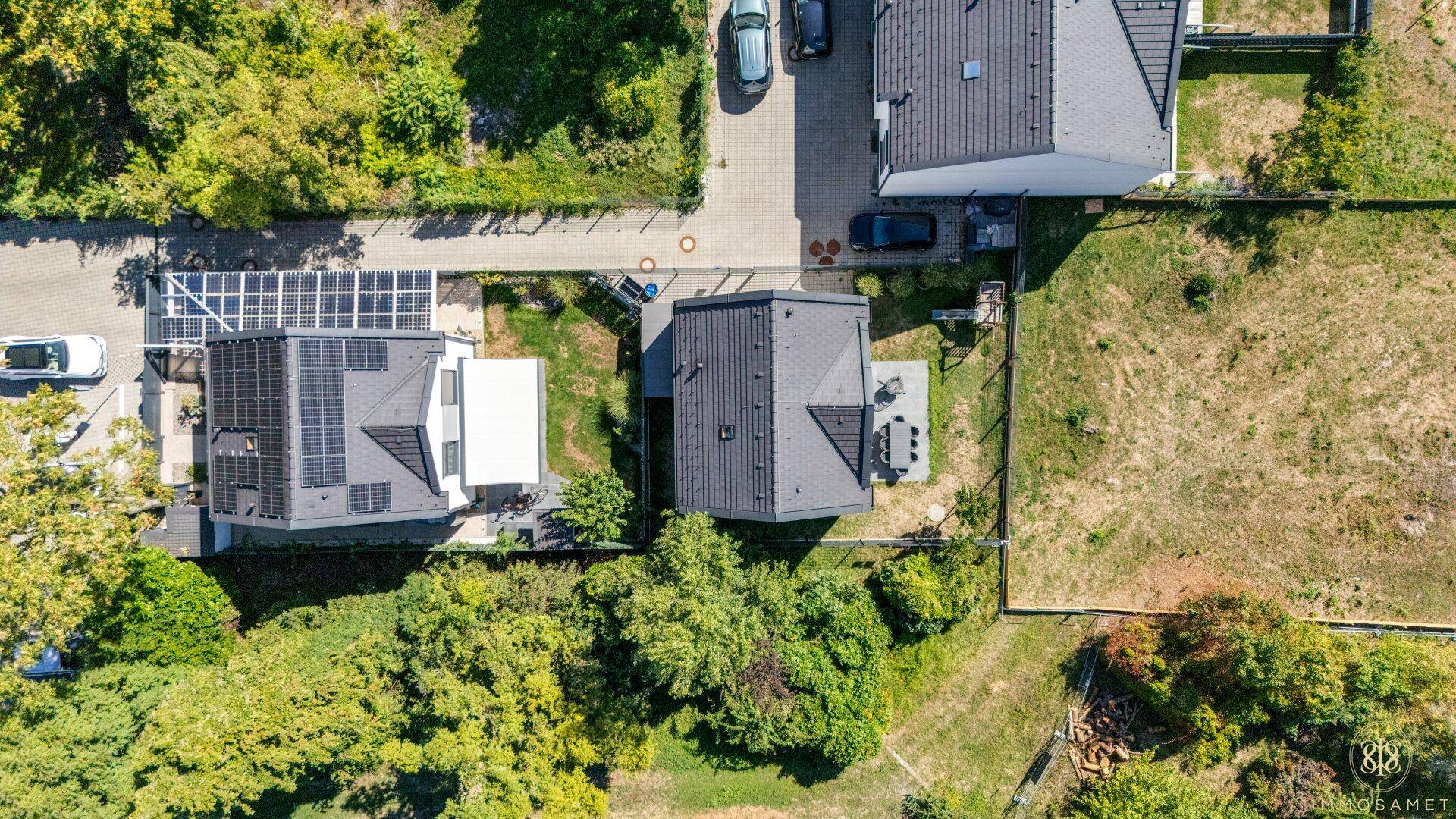 Luftaufnahme von zwei modernen Häusern mit Photovoltaikanlagen auf den Dächern und umliegender Natur.