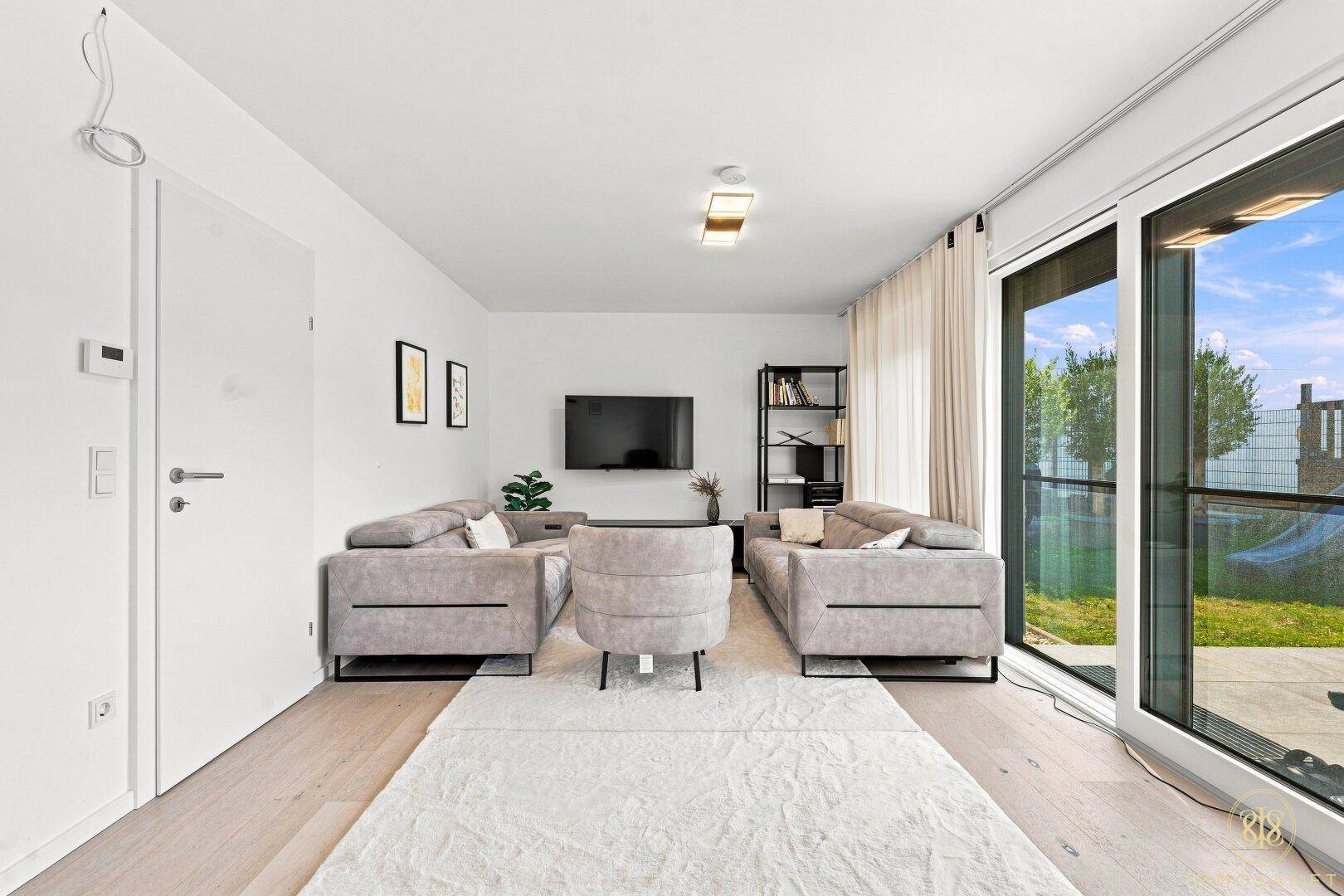 Geräumiges Wohnzimmer mit minimalistischer Einrichtung und viel Tageslicht.