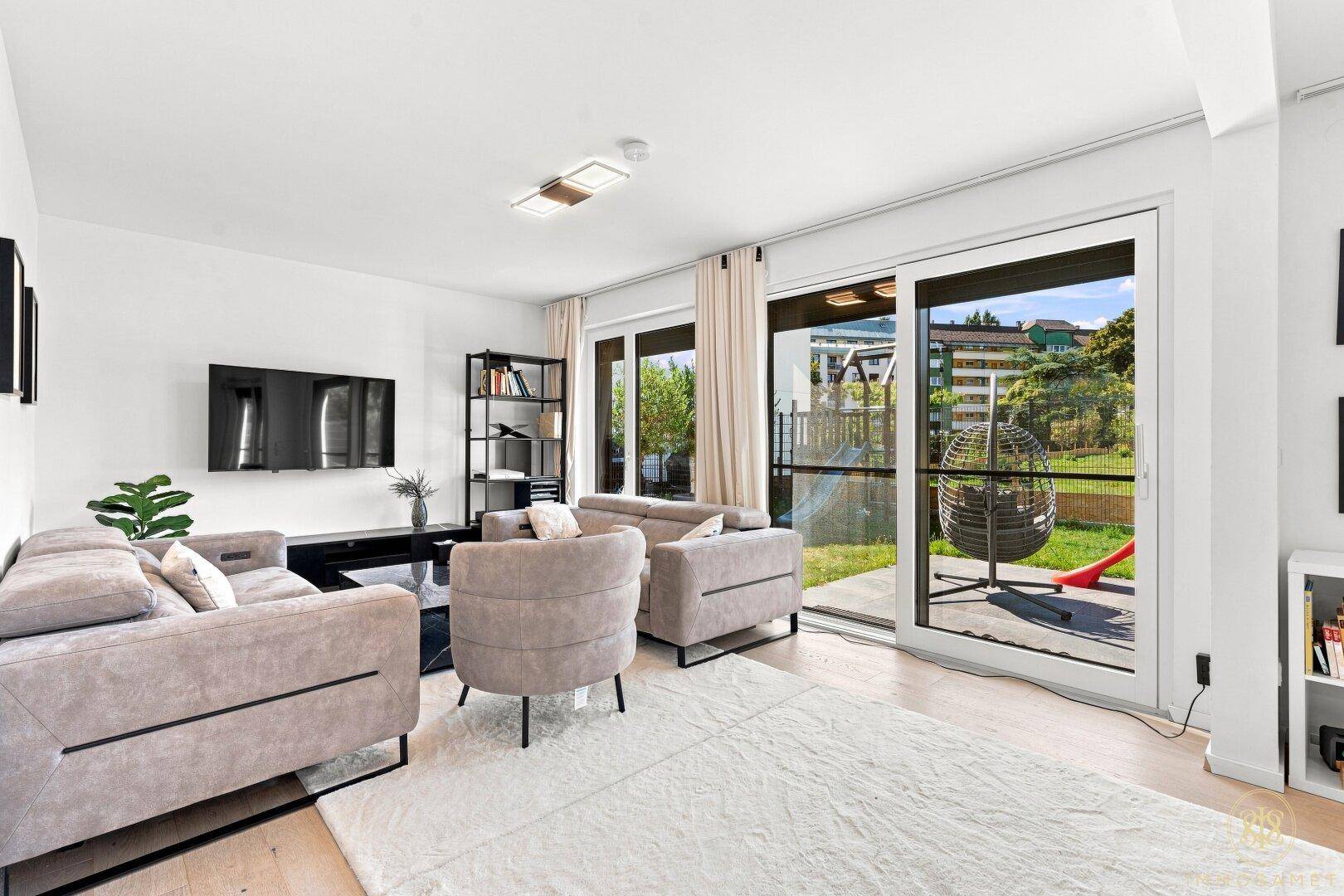Helles Wohnzimmer mit bequemen Sofas, großem Teppich und Zugang zur Terrasse.