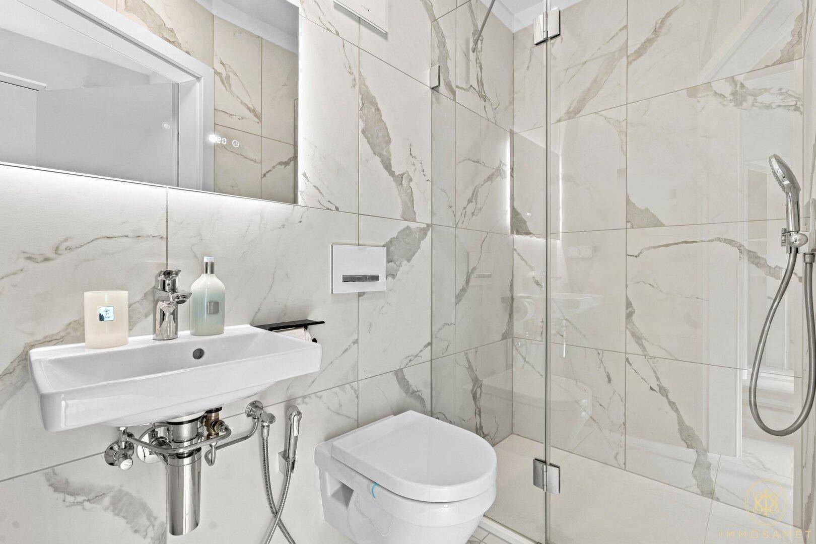 Modernes Badezimmer mit Marmorfliesen, wandhängendem WC und ebenerdiger Dusche.