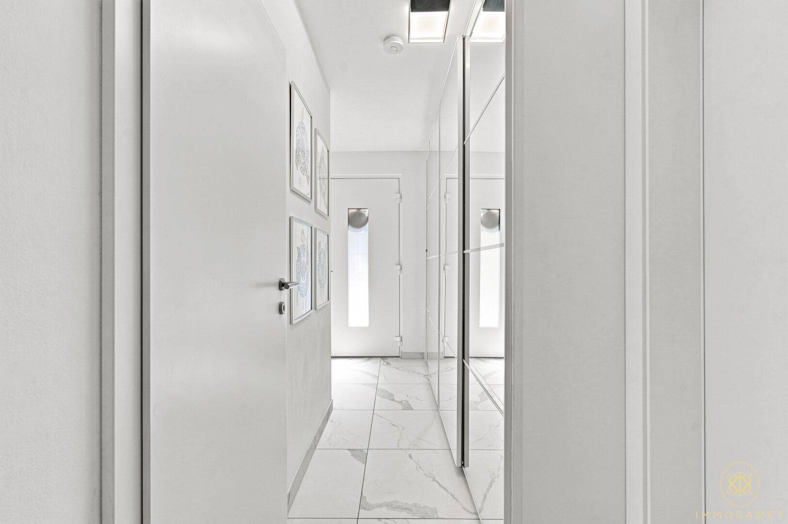 Heller Flur mit modernen Fliesen und einem großen Spiegelschrank.