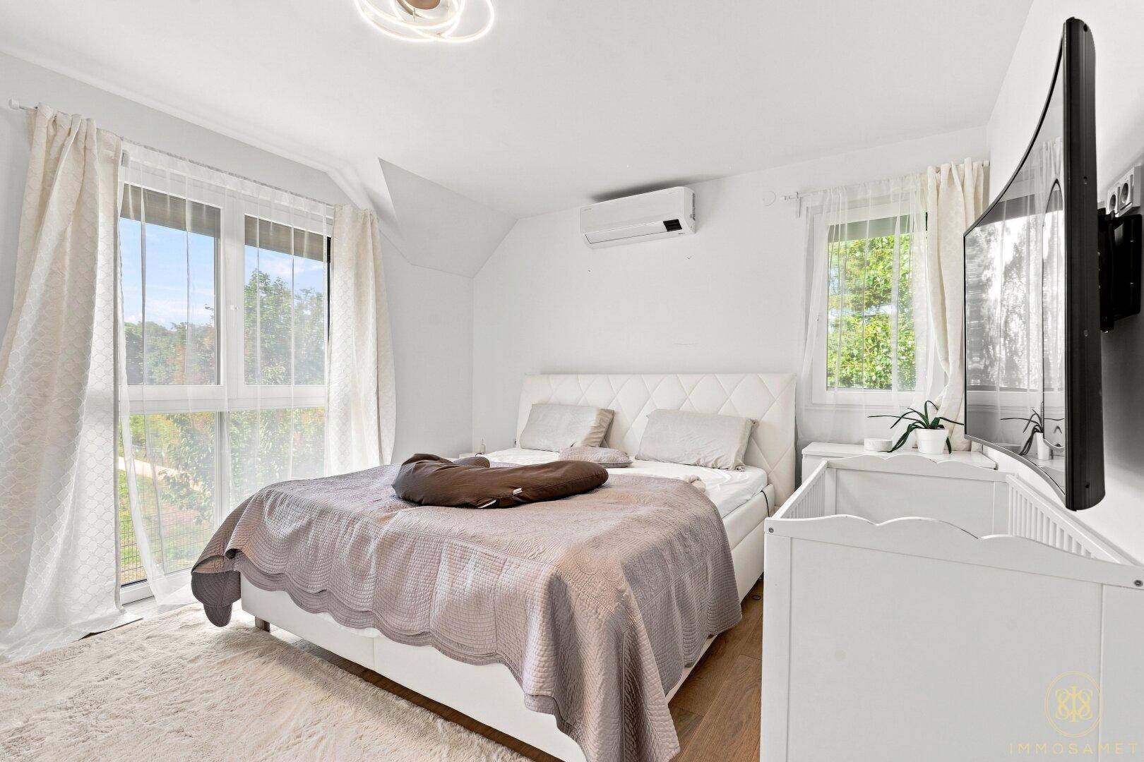 Geräumiges Schlafzimmer mit Doppelbett, Klimaanlage und Zugang zum Balkon.