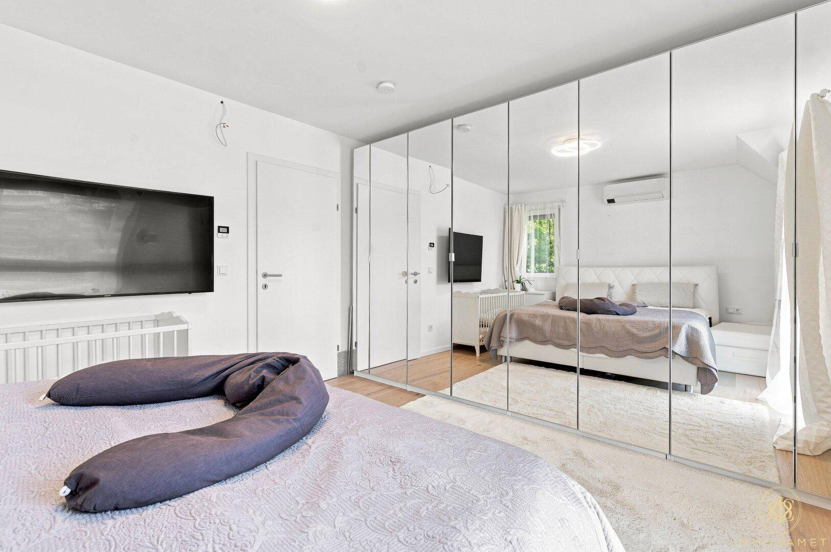 Schlafzimmer mit großem Spiegelschrank, Doppelbett und viel Tageslicht.