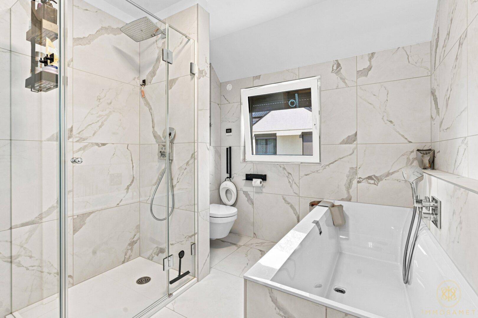 Luxuriöses Badezimmer mit Badewanne, ebenerdiger Dusche und Marmorfliesen.