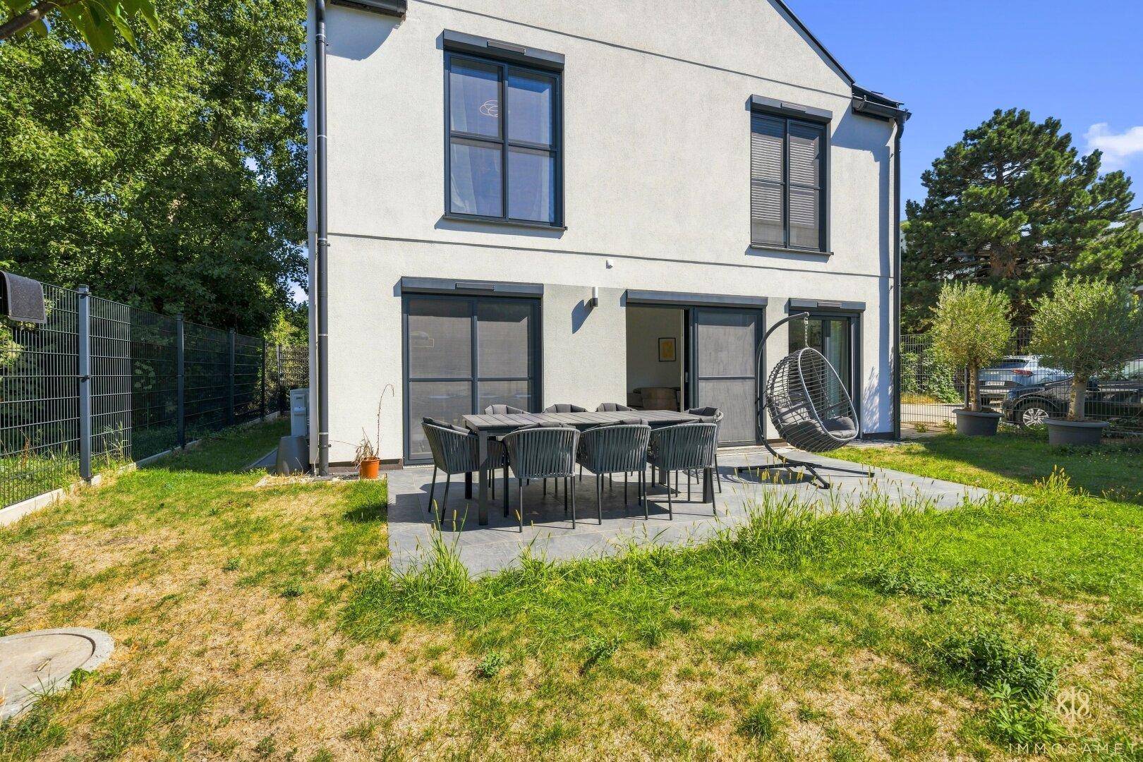 Geräumige Terrasse mit Essbereich und angrenzendem Garten hinter dem modernen Haus.