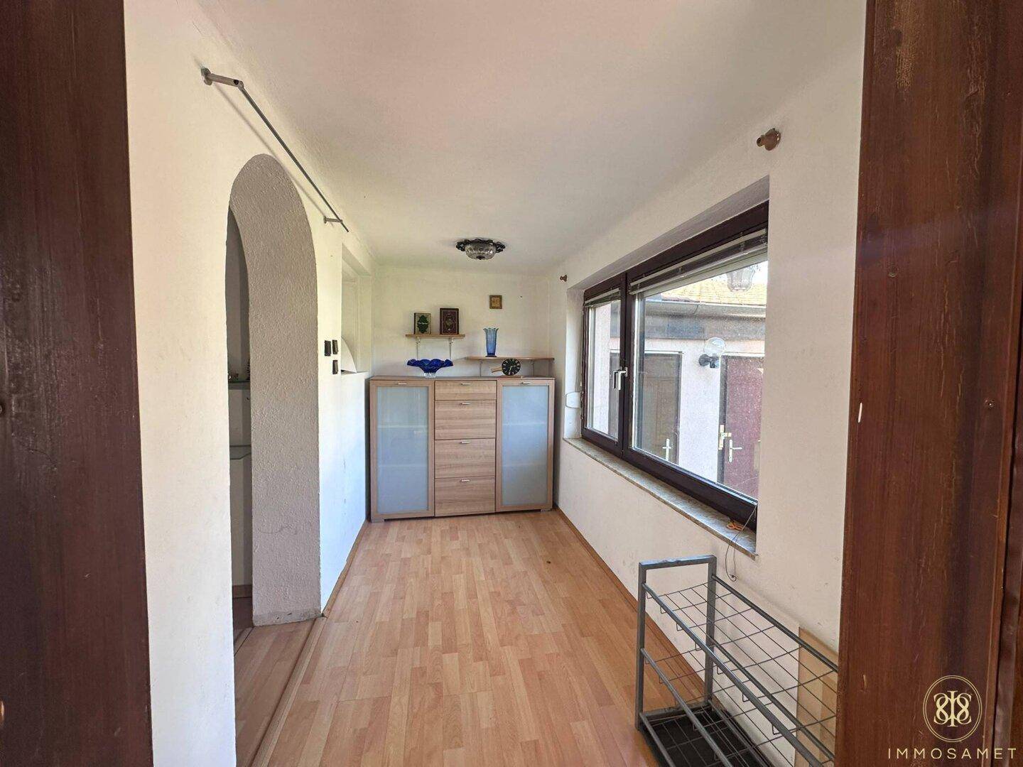 Heller Flur mit großem Fenster, Holzschrank und Blick in den Garten.