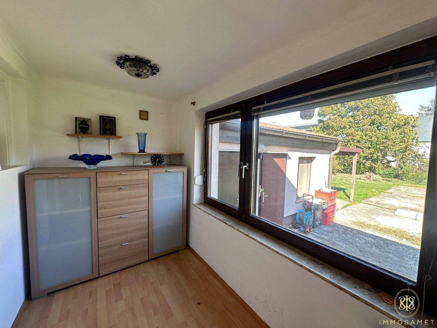 Geräumiger Flur mit großem Fenster, Holzschrank und viel Tageslicht.
