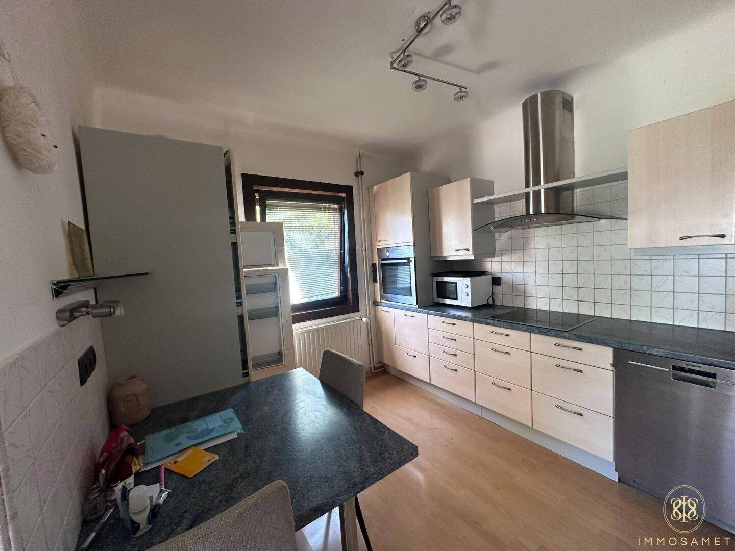 Gut ausgestattete Küche mit Kühlschrank, Backofen und kleinem Esstisch am Fenster.