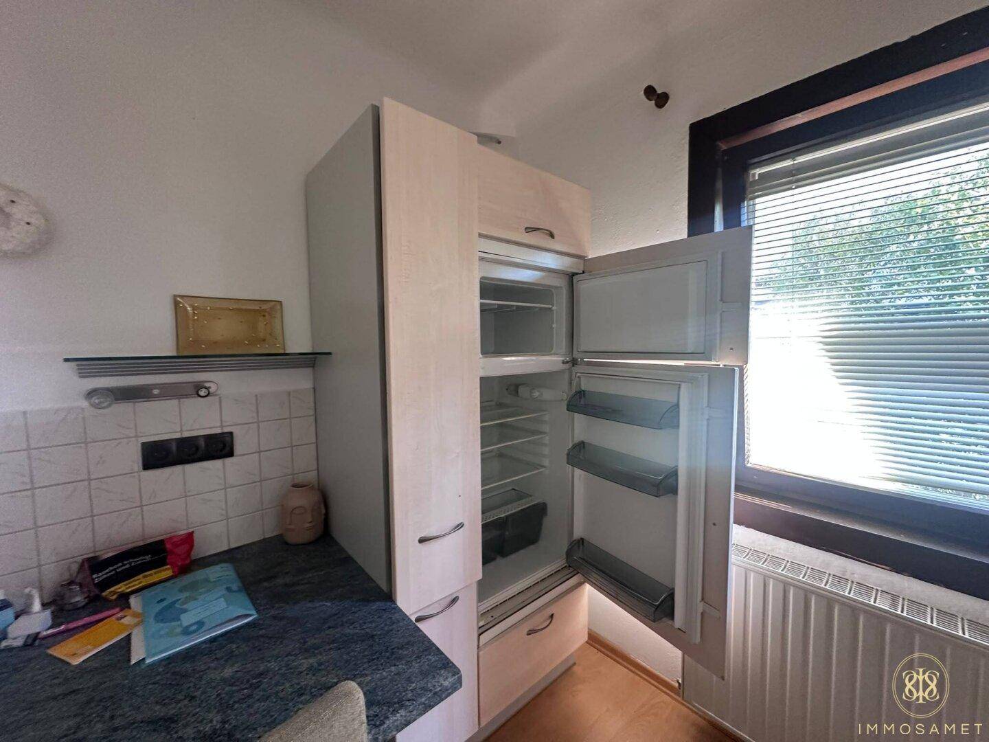 Integrierter Kühlschrank mit Gefrierfach in der hellen Einbauküche.