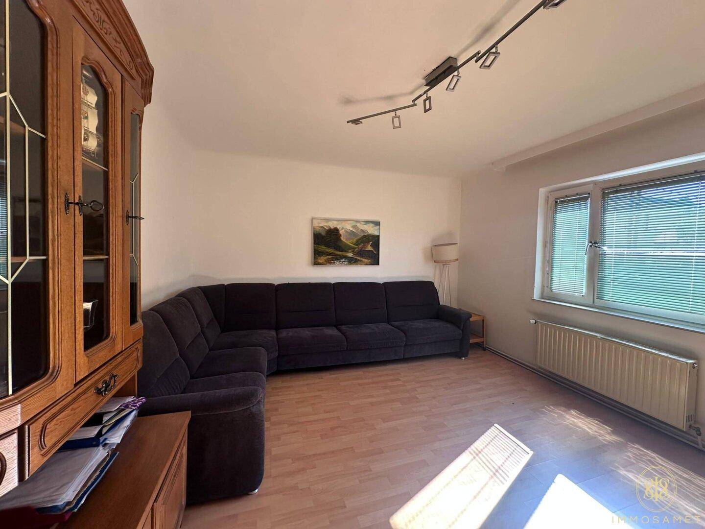Gemütlicher Wohn- und Essbereich mit großem Ecksofa und Laminatboden, ideal zum Entspannen.