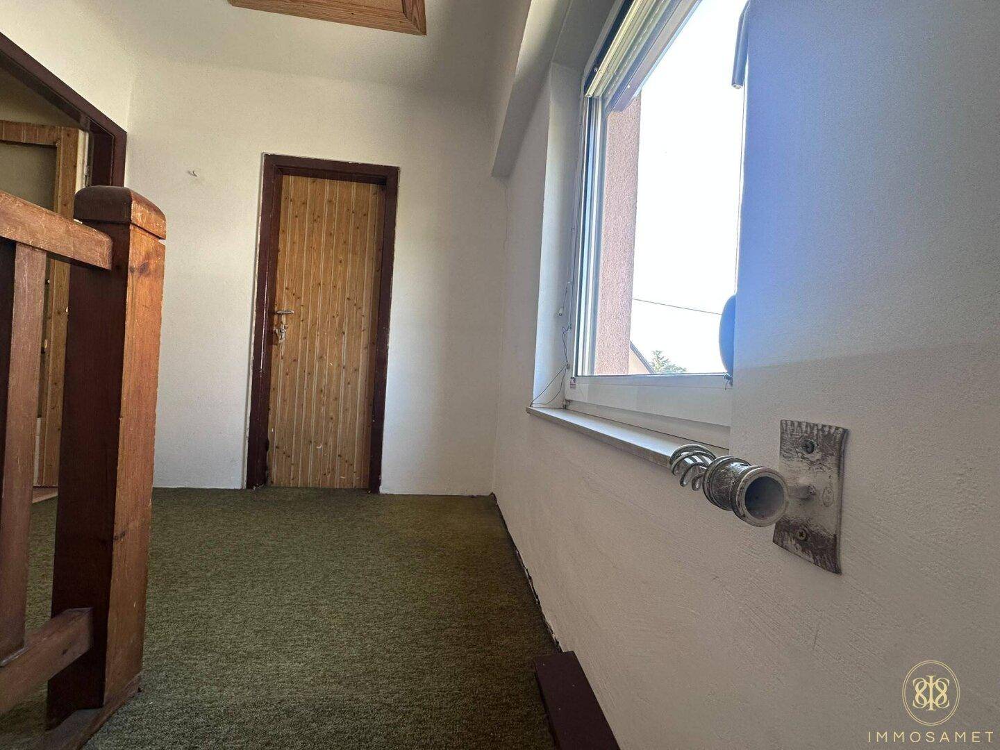 Obergeschoss-Flur mit Teppichboden und Fenster, bietet Zugang zu den oberen Zimmern.