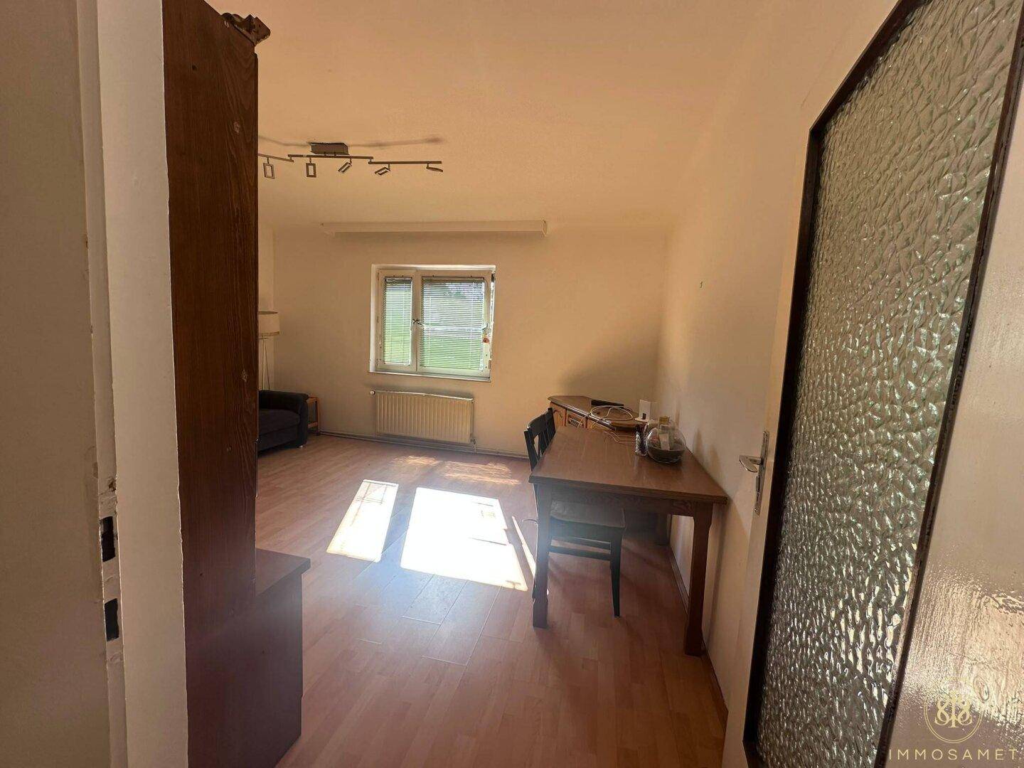 Geräumiger Wohn- und Essbereich mit Laminatboden und viel Tageslicht, ideal für Familienleben.