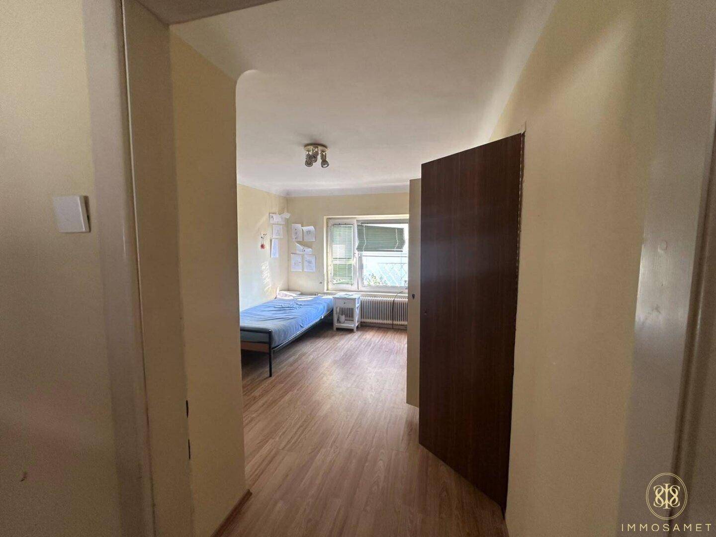 Schlafzimmer mit Einzelbett und Laminatboden, bietet eine einfache und funktionale Einrichtung.