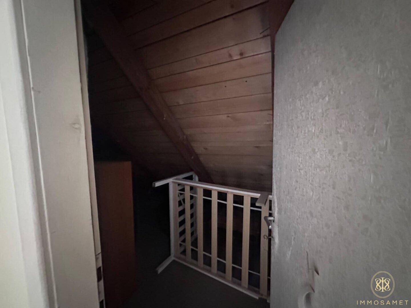 Abstellraum im Dachgeschoss mit schrägen Holzwänden und Stauraum für diverse Gegenstände.