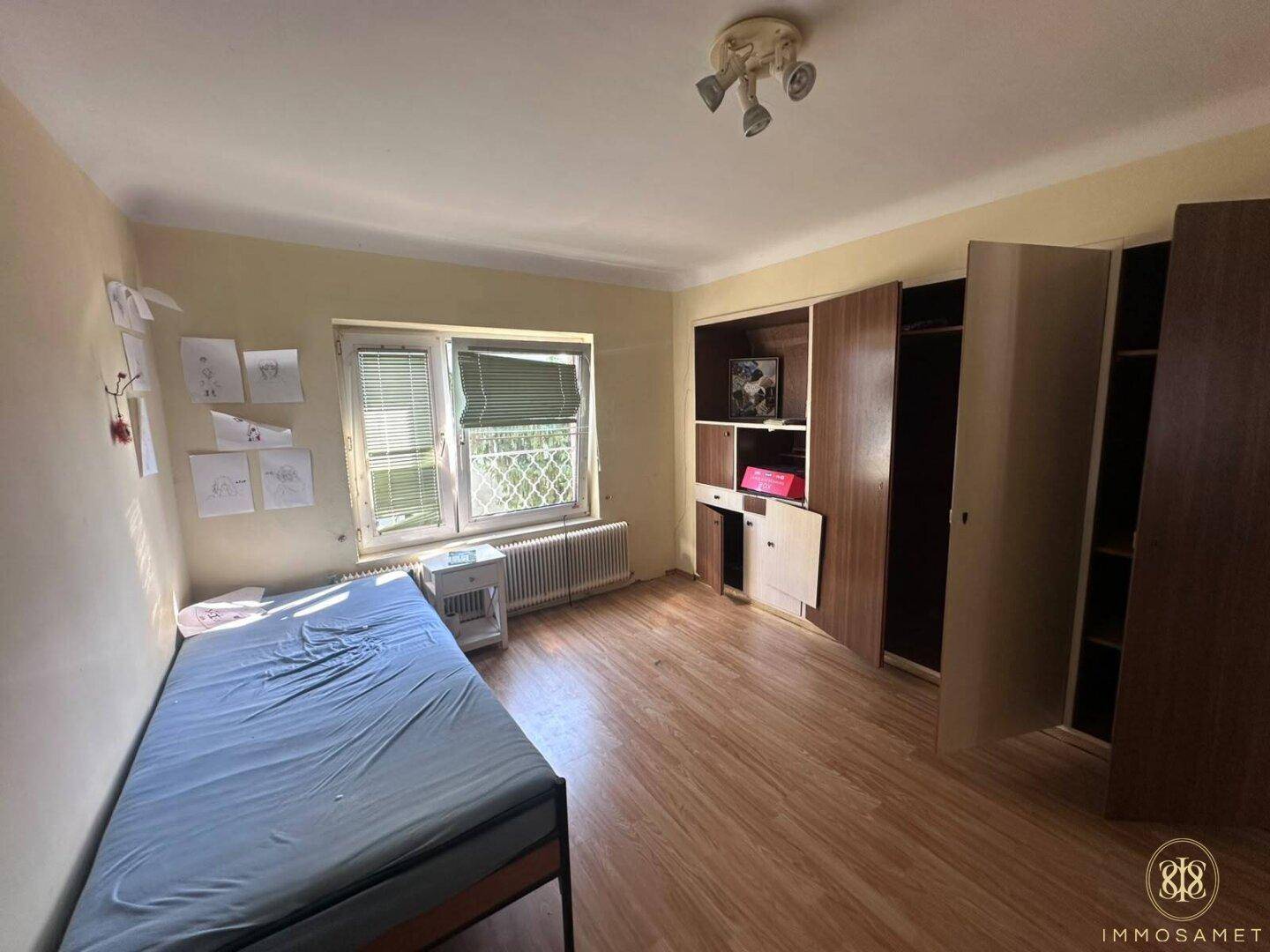 Schlafzimmer mit Einzelbett, Laminatboden und Einbauschränken, bietet praktischen Stauraum.